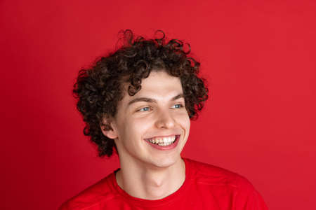 Cropped portrait of young cheerful man in casual cloth smiling isolated over red backgroundの写真素材