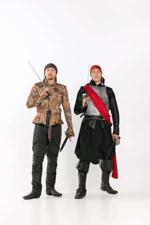 Full-length portrait of two men in vitage costumes knight of the road and pirate isolated over white backgroundの写真素材