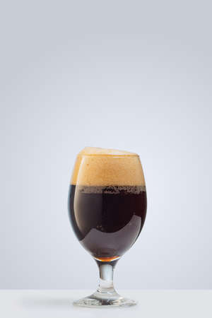 Glass of dark foamy beer isolated over gray background. Concept of alcohol drinks, partyの写真素材