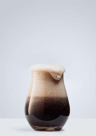 Glass of dark foamy beer isolated over gray background. Concept of alcohol drinks, partyの写真素材