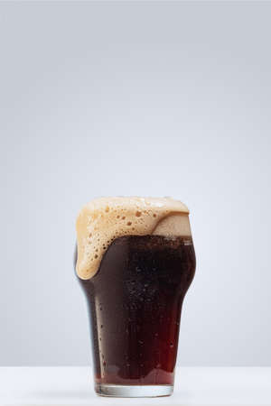 Glass of dark foamy beer isolated over gray background. Concept of alcohol drinks, partyの写真素材