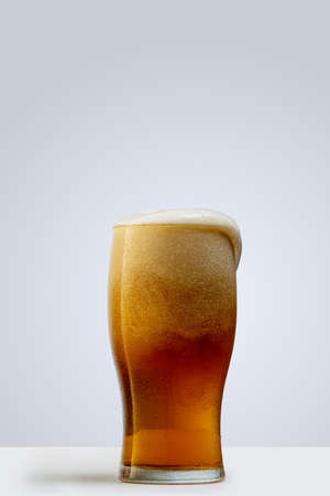 Glass of lager foamy beer isolated over gray background. Concept of alcohol drinksの写真素材