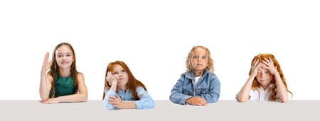 Collage of four children, girls, pupils sitting at the table with different emotions isolated over...