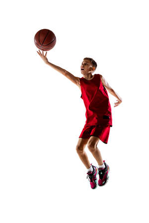 Full-length portrait of boy, basketball player training, throwing ball into the basket isolated over white background.の写真素材
