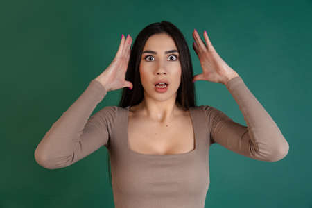 Cropped portrait of young girl with expressive shocked emotions isolated over green backgroundの写真素材