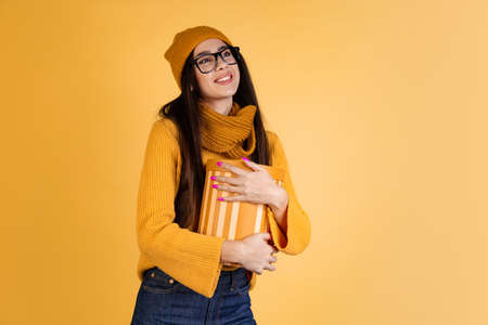 Cropped portrait of happy smiling woman with big present box isolated over yellow background