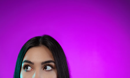 Cropped image of beautiful female eyes looking left side isolated over purple background