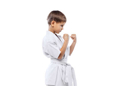 Cropped portrait of little boy in white kimono, martial art sportsman posing isolated over white backgroundの写真素材