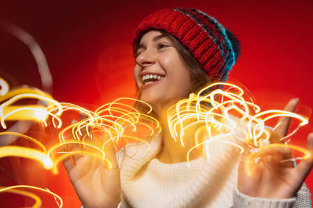 Cropped portrait of young joyful woman holiday sparkles isolated over red background. Celebrationsの写真素材