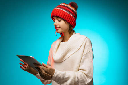 Cropped portrait of young girl holding tablet, choosing presents isolated over blue backgroundの写真素材