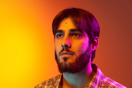 Close-up portrait of young man in checkered shirt serioussly looking at camera and posing isolated...