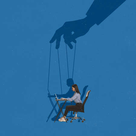Contemporary art collage. Young woman, employee working on laptop. Giant hand with string attached to girl making controlの写真素材