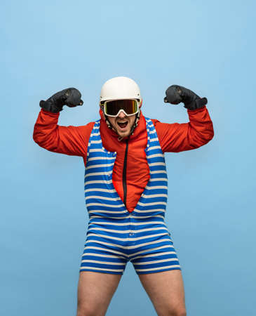Creative collage of man wearing swimming suit above sportswear, ski costume isolated over blue backgroundの写真素材