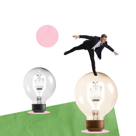 Contemporary art collage. Young man, employee, manager balancing on light bulb symbolizing ideas developmentの写真素材