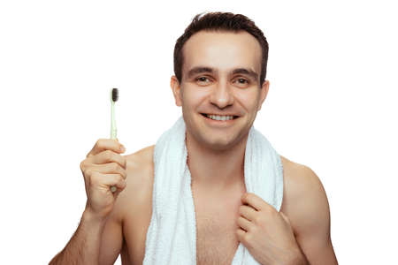 Portrait of smiling man holding toothbrush, cleaning mouth isolated over white studio backgroundの写真素材
