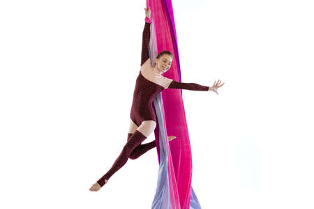 Portrait of young woman, air gymnast training on ribbon isolated over white studio background. Beautiful performance. Concept of sport, action, lifestyle, beauty, hobby. Copy space for adの写真素材