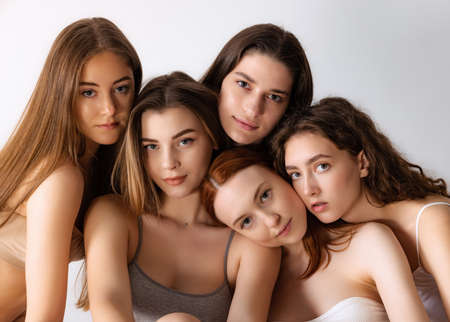 Portrait of beautiful young women with nude makeup posing, looking at camera isolated over grey studio background. Concept of beauty, body and skin care, health, spa, cosmetics, cosmetology, adの写真素材