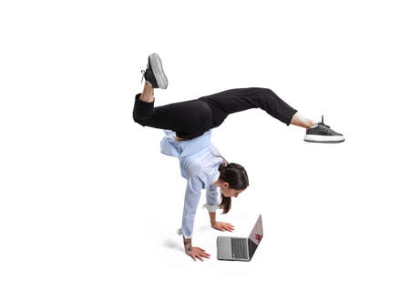 Portrait of concentrated office worker standing on hands and working with laptop isolated over white studio background. Concept of business, office lifestyle, success, ballet, career, expression, adの写真素材