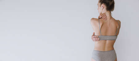 Rear view portrait of cropped female body, back isolated over grey studio background. Model wearing underwear. Massage treatment. Concept of beauty, body and skin care, health, spa, cosmetics, adの写真素材