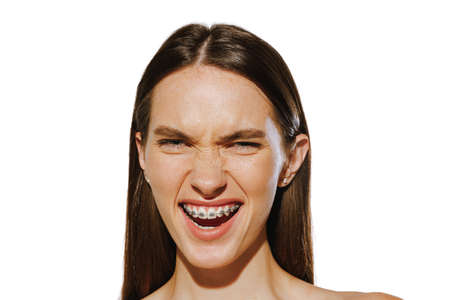 Portrait of beautiful young girl with braces. smiling, posing isolated over white background. Dental...