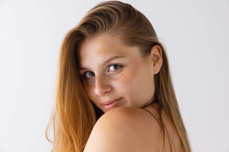 Close-up portrait of beautiful young girl with natural looking freckles face, looking at camera...