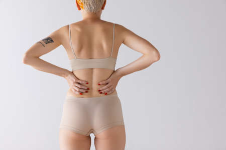 Cropped image of female body, back buttocks in beige underwear isolated over grey studio background. Strong back muscles. Concept of beauty, body and skin care, health, plastic surgery, cosmetics, adの写真素材