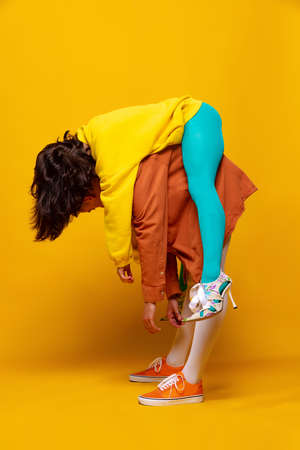 Creative colorful portrait of man and woman in bright clothes with posing isolated over yellow...