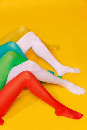 Creative colorful portrait of legs in bright rights isolated over yellow studio background. Vintage...