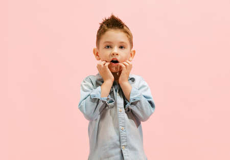 Portrait of little boy, child in jeans t-shirt posing, making faces isolated over pink background. Emotinal kid. Concept of childhood, family, emotions, lifestyle, fashion, wellness, adの写真素材