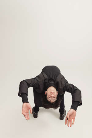 Portrait of extraordinary young man in stylish total black outfit posing isolated over grey studio...