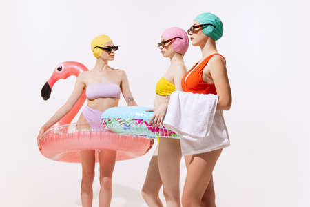 Young women in swimming suit, cap and sunglasses posing with swimming circle isolated over grey studio background. Concept of beauty, fashion, vintage style, summertime, party. Copy space for adの写真素材