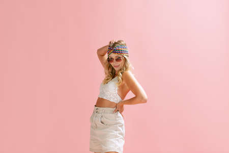 Portrait of stylish young woman posing isolated over pink studio background. Summer festival outfit. Concept of beauty, emotions, facial expression, lifestyle, fashion, youth cultureの写真素材