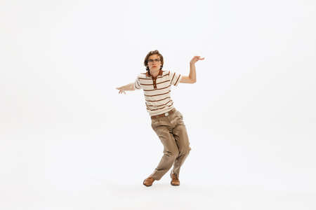 Portrait of expressive young man in vintage outfit dancing, posing isolated over white studio background. Feeling good. Concept of retro fashion, style, youth culture, emotions, beauty, adの写真素材