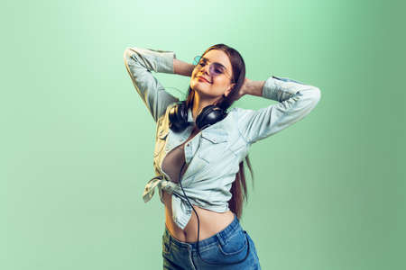Portrait of young girl in casual clothes posing isolated over green studio background. Looks happy...