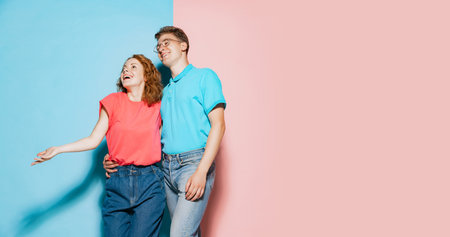 Portrait of young cheerful couple, posing, smiling isolated over pink blue studio background. Happy and delightful. Concept of youth, emotions, facial expression, love, relationship. Poster, adの写真素材