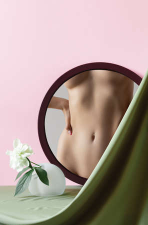 Female body, back on mirror reflection with flower. Body art, aesthetics. Fabric elements on pink background. Beauty, womens heath, attraction, cosmetology, plastic surgery concept. Copy space for adの写真素材