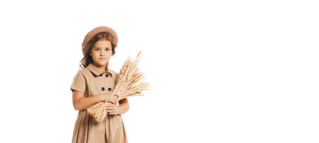 Portrait of little girl, child in stylish vintage outfit posing with spikelets of wheat isolated over white studio background. Concept of childhood, friendship, fun, lifestyle, fashion. Retro styleの写真素材