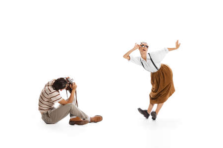 Portrait of man taking photo of beautiful stylish woman in a jump isolated on white background. Retro style. Concept of business, office lifestyle, success, ballet, career, expression, adの写真素材