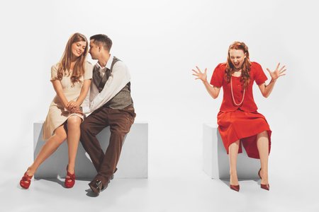 Portrait of young angry girl finding out man cheating her with another woman. Unfaithful relationship. Concept of retro fashion, style, youth culture, emotions, relationship, adの写真素材