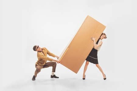 Portrait of young man and woman carrying giant cardboard boxes. New apartment furniture shopping. Moving into new flat. Concept of retro fashion, style, youth culture, emotions, adの写真素材