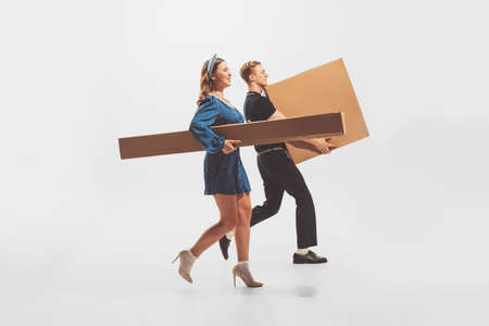 Young man and woman carrying big cardboard boxes isolated over white background. Black Friday...