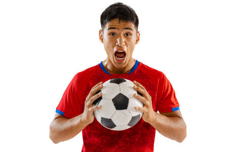 Portrait of young emotive man, football player in red uniform posing with ball isolated over white studio background. Concept of sport, team game, action, motion. Copy space for ad, posterの写真素材