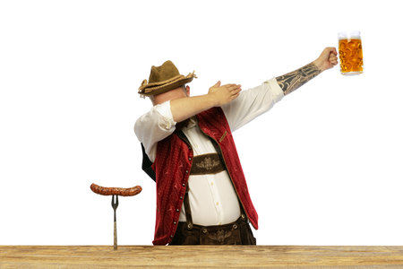 Portrait of young man wearing traditional Bavarian or German clothes isolated over white background. Cheerful beer party. Alcohol, Oktoberfest festival, traditions, taste concept. Copy space for adの写真素材