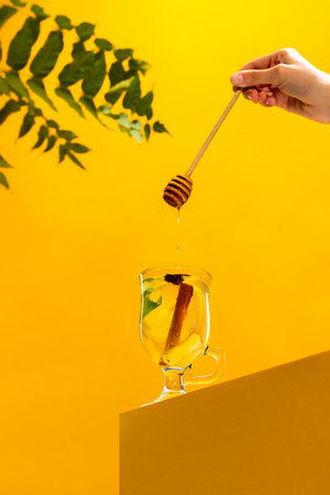 Teacup with delicious herbal tea with citrus, lemons, ginger, honey and mint isolated over yellow background. Concept of taste, drink, healthy ingredients, seasonal drink. Copy space for adの写真素材