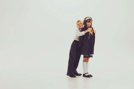 Portrait of little children, boy and girl in stylish vintage outfit, posing isolated over grey studio background. Concept of childhood, friendship, fun, lifestyle, fashion, retro styleの写真素材