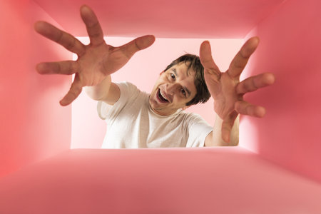 Emotive, smiling man looking inside carton box with hands, expressive face. Delivery service. Concept of gifts, shopping, emotions, facial expression. Unpacking box.の写真素材