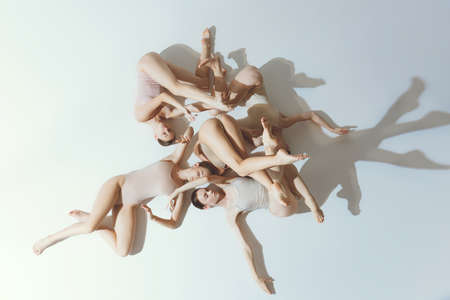 Group of young girls, ballet dancers performing, posing isolated over grey background. Extraordinary movements. Top view. Concept of art, beauty, aspiration, creativity, classic dance style, eleganceの写真素材