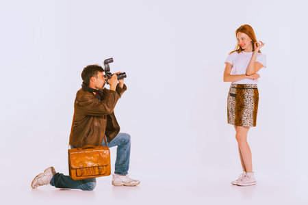 Portrait of young people, man taking photo of beautiful girl isolated over grey background. Cheerfully posing. Concept of youth, retro style, 90s era, fashion, lifestyle, friendship, adの写真素材