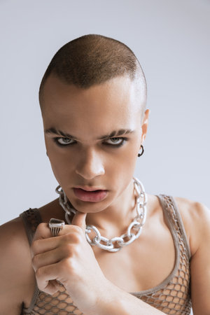 Close-up portrait of stylish young man with makeup posing isolated over grey studio background. Male expression. Concept of fashion, freedom of choice, lifestyle, lgbt, generation z, trendsの写真素材