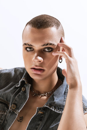Portrait of young man with smoky eyes makeup posing in black jeans shirt isolated over white background. Attentive look. Concept of fashion, freedom of choice, lifestyle, lgbt, generation z, trendsの写真素材